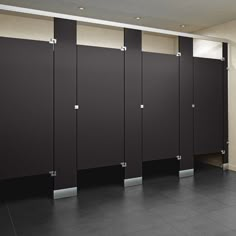 a row of black and white stalls next to each other in a room with tile flooring