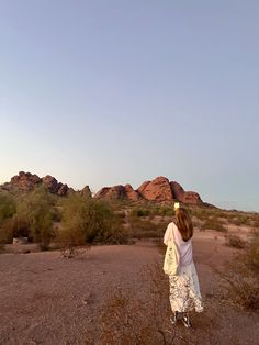 a woman is flying a kite in the middle of desert land with rocks and bushes