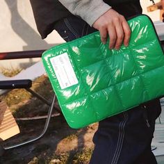 a person holding a green bag with a tag on it