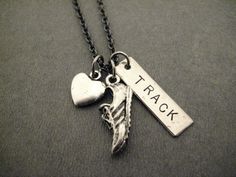 a necklace with an arrow, heart and tag that says track on it's back