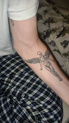 a man with a tattoo on his arm and leg is laying down next to a bed