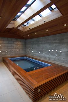 an indoor jacuzzi in the middle of a room with skylights above it