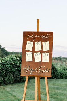 a wooden easel with notes attached to it in front of some grass and bushes