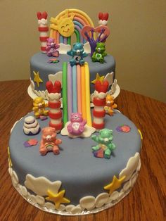 a birthday cake decorated with rainbows, stars and other decorations on a table top