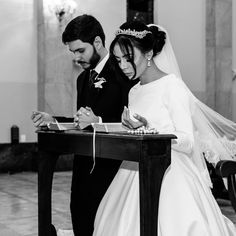 a bride and groom signing their marriage vows at the alter in black and white photo