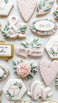 many decorated cookies are arranged on a white tablecloth with the words love spelled in cursive writing