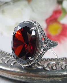 Red Garnet Ring Description Persian Design#230 MADE TO ORDER This is a brand new stunning Art Nouveau/Vintage designed sterling silver filigree 9ct oval red garnet CZ ring. The Flawless oval full cut high-quality garnet CZ is 18mm (just shy of 3/4th of an inch) by 13mm (1/2 inch) in dimension... This ring is 21mm NS on the finger. The inside of the band is marked 925 for sterling. Notice the beautiful filigree swirl like the craftsmanship of the silver setting. This lovely ring stands out and il Mystic Fire Topaz, Red Garnet Ring, Antique Filigree, Vintage Revival, Persian Design, Vintage Style Rings, Deco Vintage, Garnet Ring, Sterling Silver Filigree