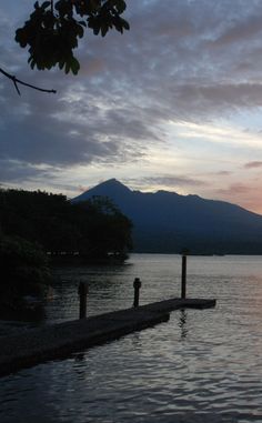 the sun is setting over water and mountains