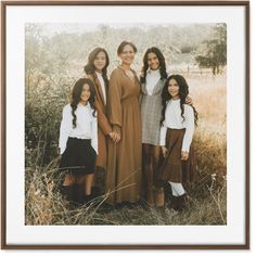 a group of women standing next to each other in front of some tall dry grass