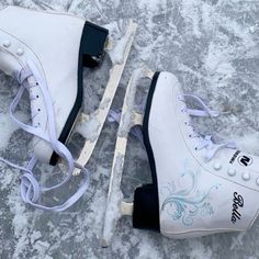 two white ice skates sitting on top of snow covered ground next to each other