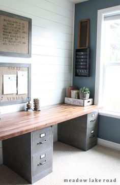 a wooden desk sitting in the corner of a room next to a window with pictures on it