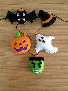 four halloween decorations hanging from strings on a table