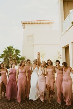 a group of women standing next to each other in front of a white building with palm trees