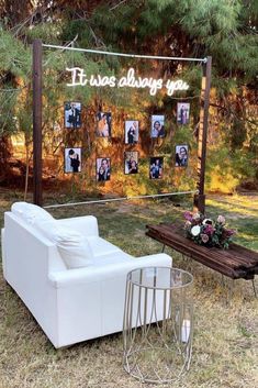 a white couch sitting on top of a grass covered field next to a wooden table