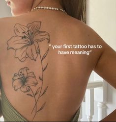 the back of a woman's tattoo with flowers on her upper and lower back