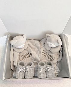 two baby shoes are in a box with the ones on it's feet and one has a teddy bear