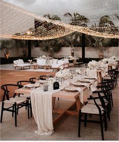 an outdoor dining area with tables and chairs, lights strung from the ceiling over them