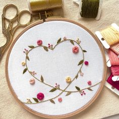 a heart shaped embroidery on a table next to scissors and spools of thread