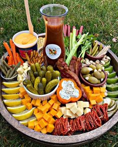 a platter filled with assorted vegetables and dips on top of green grass