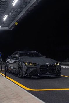 a black sports car is being fueled by a gas pump in a parking lot at night