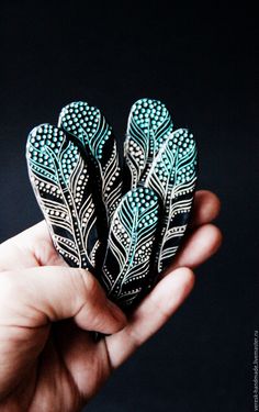 hand holding three black and white feathers in it's palm, against a dark background