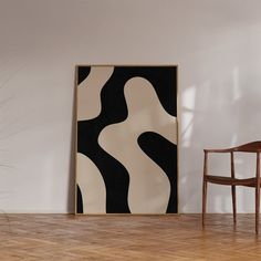 a chair sitting in front of a painting on the wall next to a wooden chair