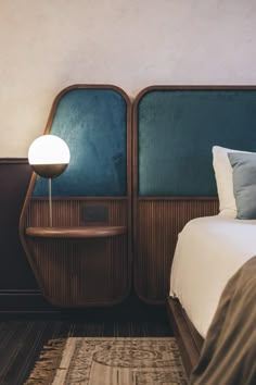 a bed sitting next to a night stand on top of a wooden floor