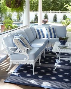 a white couch sitting on top of a blue rug under a pergolated roof