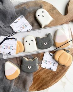 decorated cookies in the shape of cats and ghost faces on a table with halloween tags