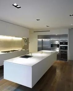 a modern kitchen with white counter tops and stainless steel appliances