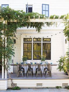 an outdoor dining table and chairs on a patio with string lights strung from the ceiling