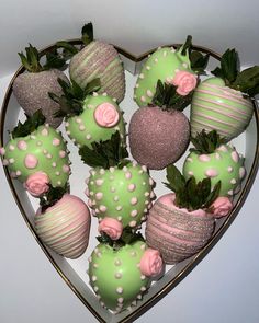 a heart shaped box filled with green and pink chocolate covered strawberries