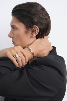 a man with his arm around his neck wearing a ring on his left hand and the other hand resting against his shoulder