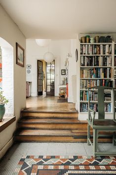 a room filled with lots of books and furniture next to a doorway that leads to another room