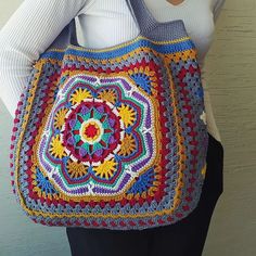 a woman is holding a crocheted bag