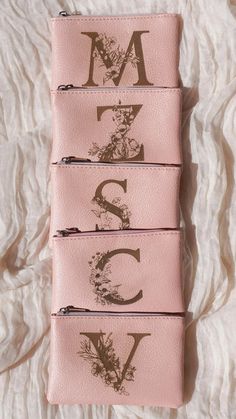 three pink wallets with the letters m, s, and c on them