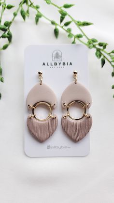 a pair of pink and gold earrings sitting on top of a white card