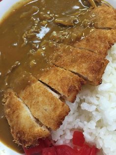 a white plate topped with rice and meat covered in gravy