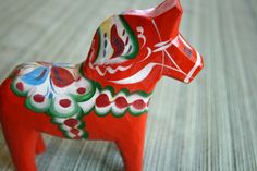 a red and white horse figurine sitting on top of a wooden table next to a wall