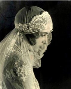 an old black and white photo of a woman wearing a veil