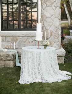 a white cake sitting on top of a table in front of a building with candles