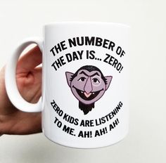 a hand holding a white coffee mug with the words, the number of the day is zero