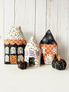 three small houses made out of fabric with pumpkins