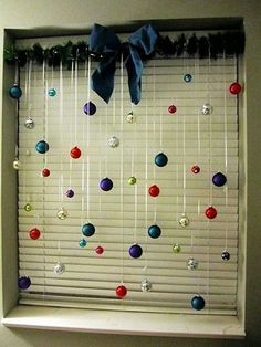 the window is decorated with balls hanging on a rod and ribbon tied at the top