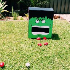 a green box sitting on top of a lush green field next to red soccer balls