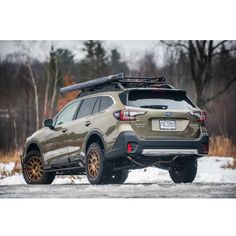 the rear end of a brown and black subarunt parked on snow covered ground