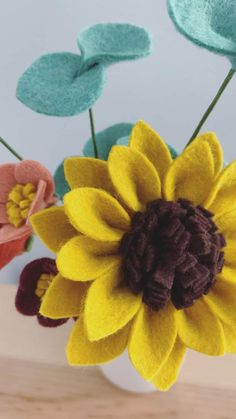 three felt flowers in a vase on a table