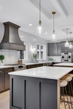 a large kitchen with an island in the middle and two pendant lights hanging from the ceiling