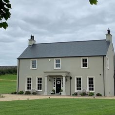 a large gray house sitting on top of a lush green field