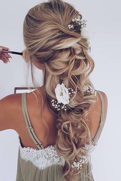 a woman with long blonde hair and flowers in her hair is holding a brush to her side